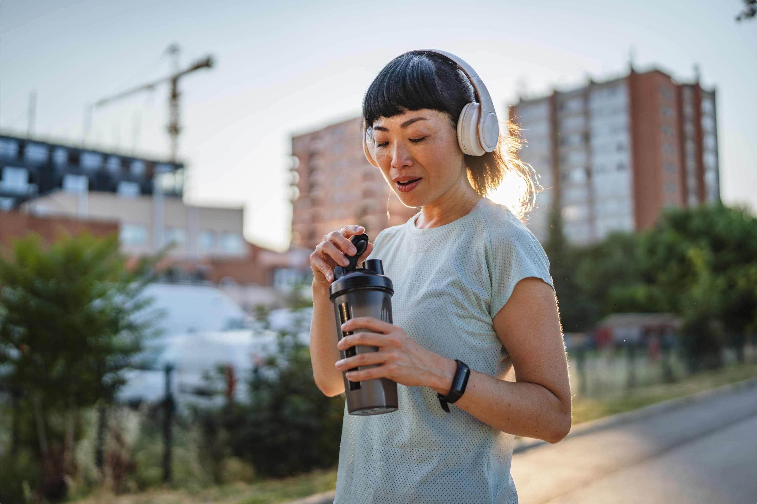 Woman in headphones opening a shaker bottle